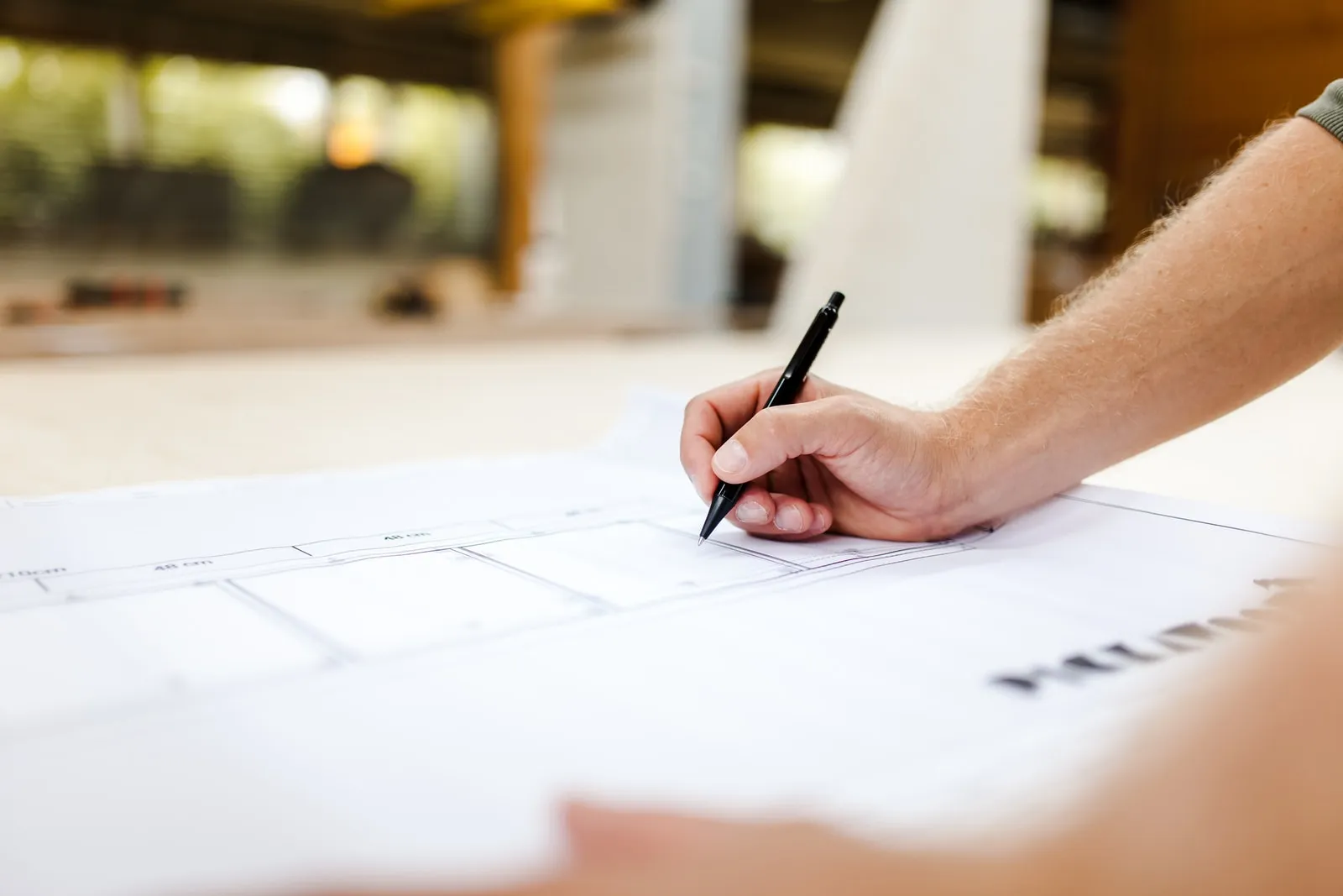 Person writing on construction plans